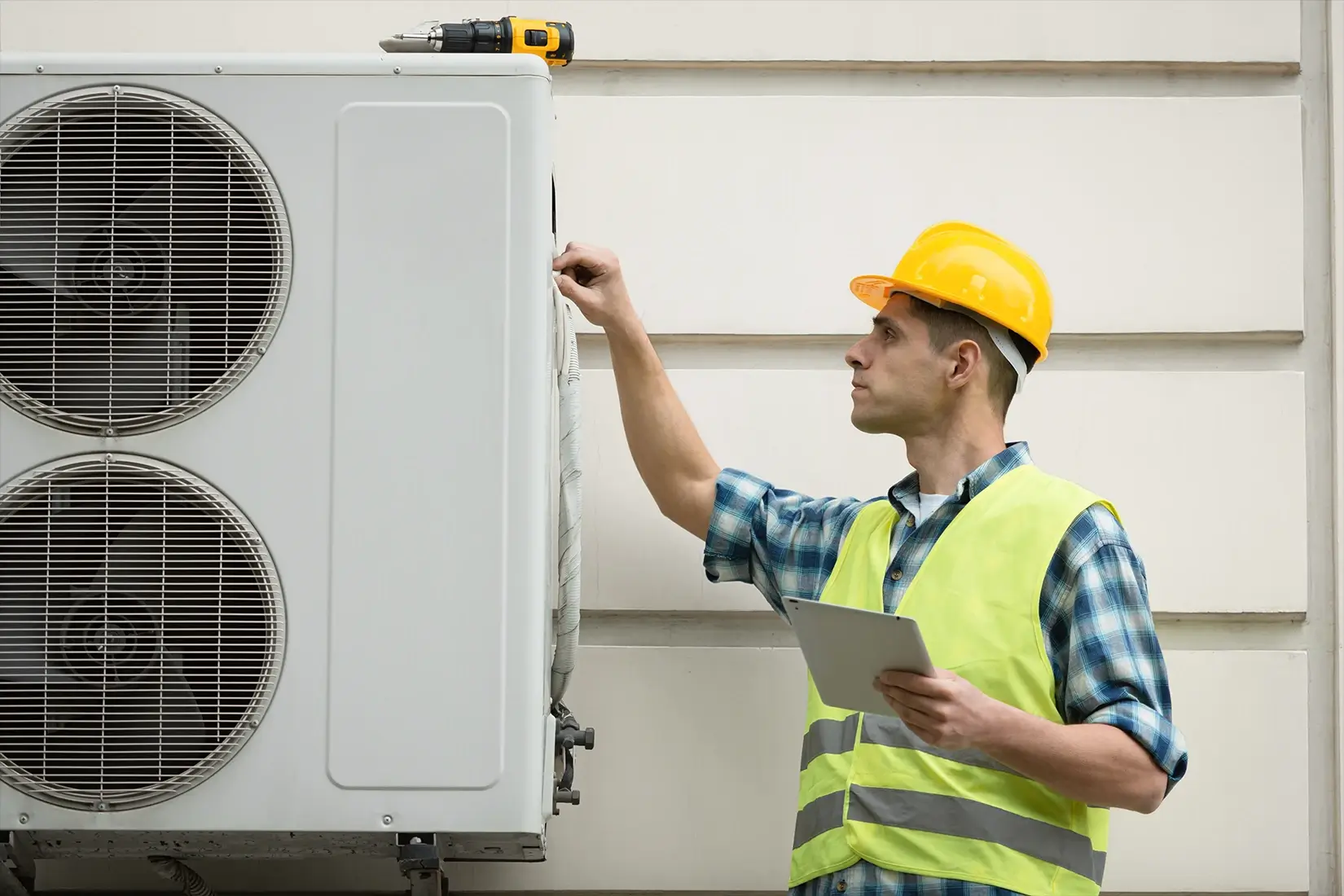 A worker servicing an air conditioner unit